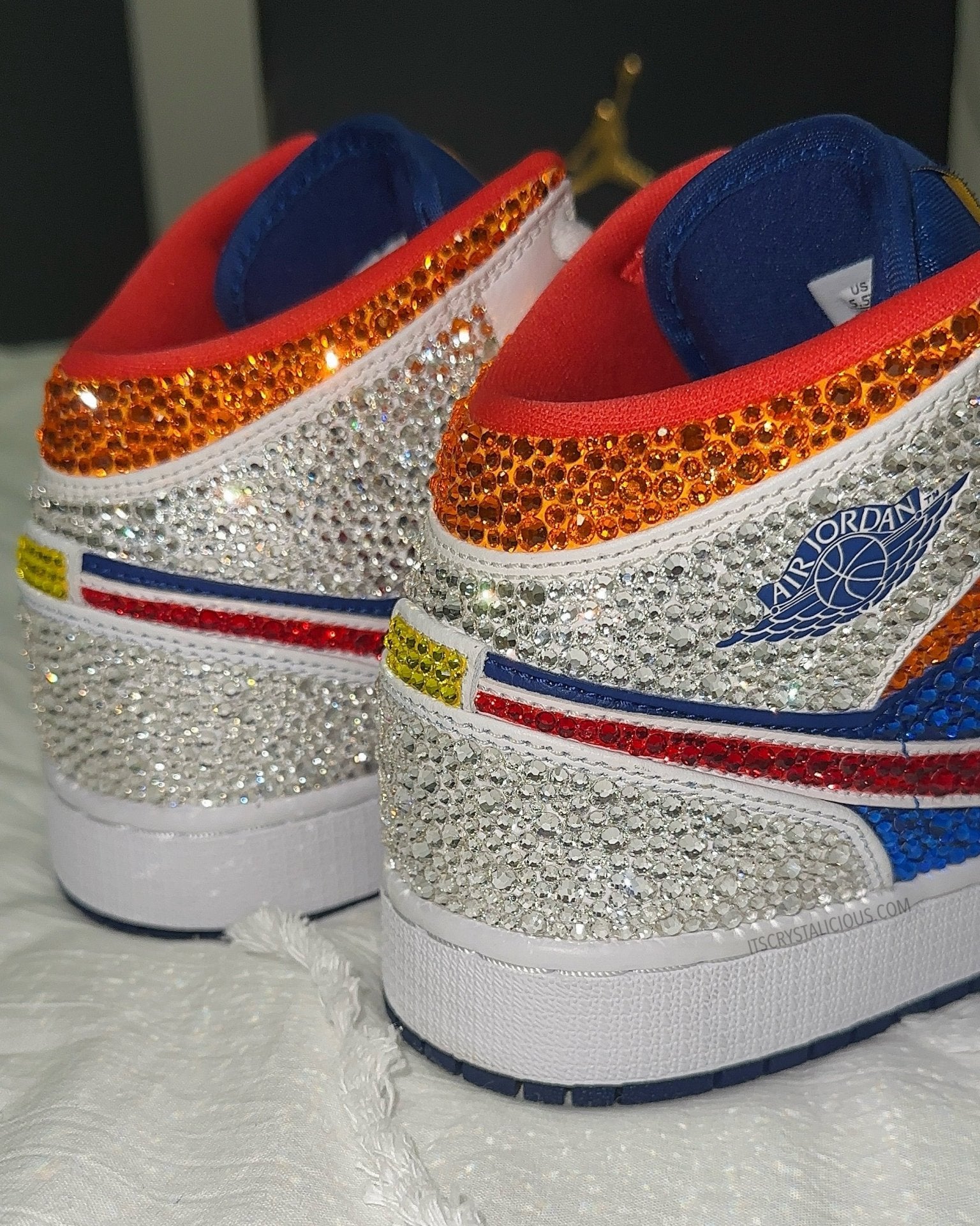 Pair of crystal embellished mid sneakers with blue, red, and white design on a textured white background