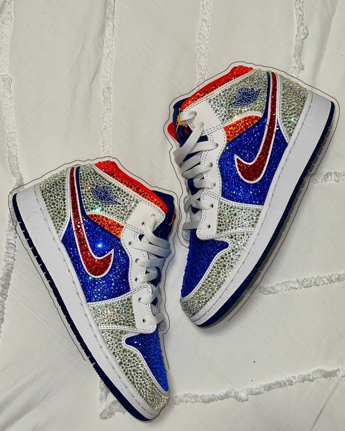 Pair of crystal embellished mid sneakers with blue, red, and white design on a textured white background