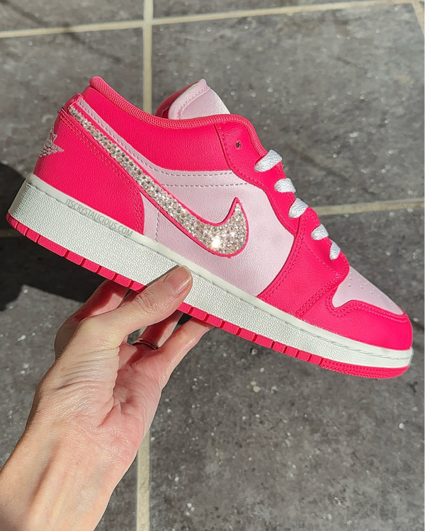 Pink sneaker with a large Nike logo held by a hand on a tiled floor.