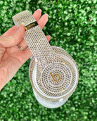 Hand holding a blinged-out electronic device against a green grass background