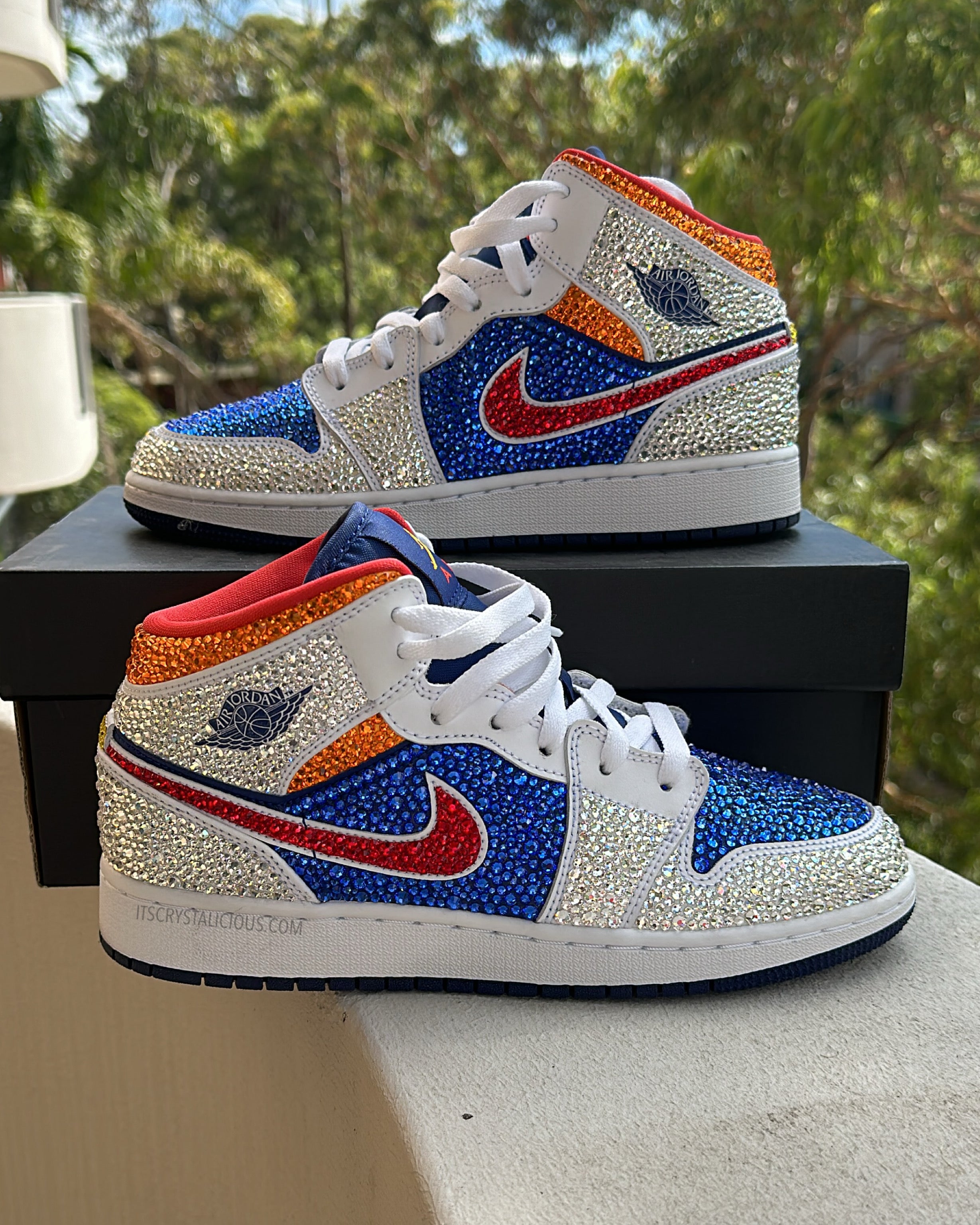 Pair of crystal embellished mid sneakers with blue, red, and white design on a textured white background