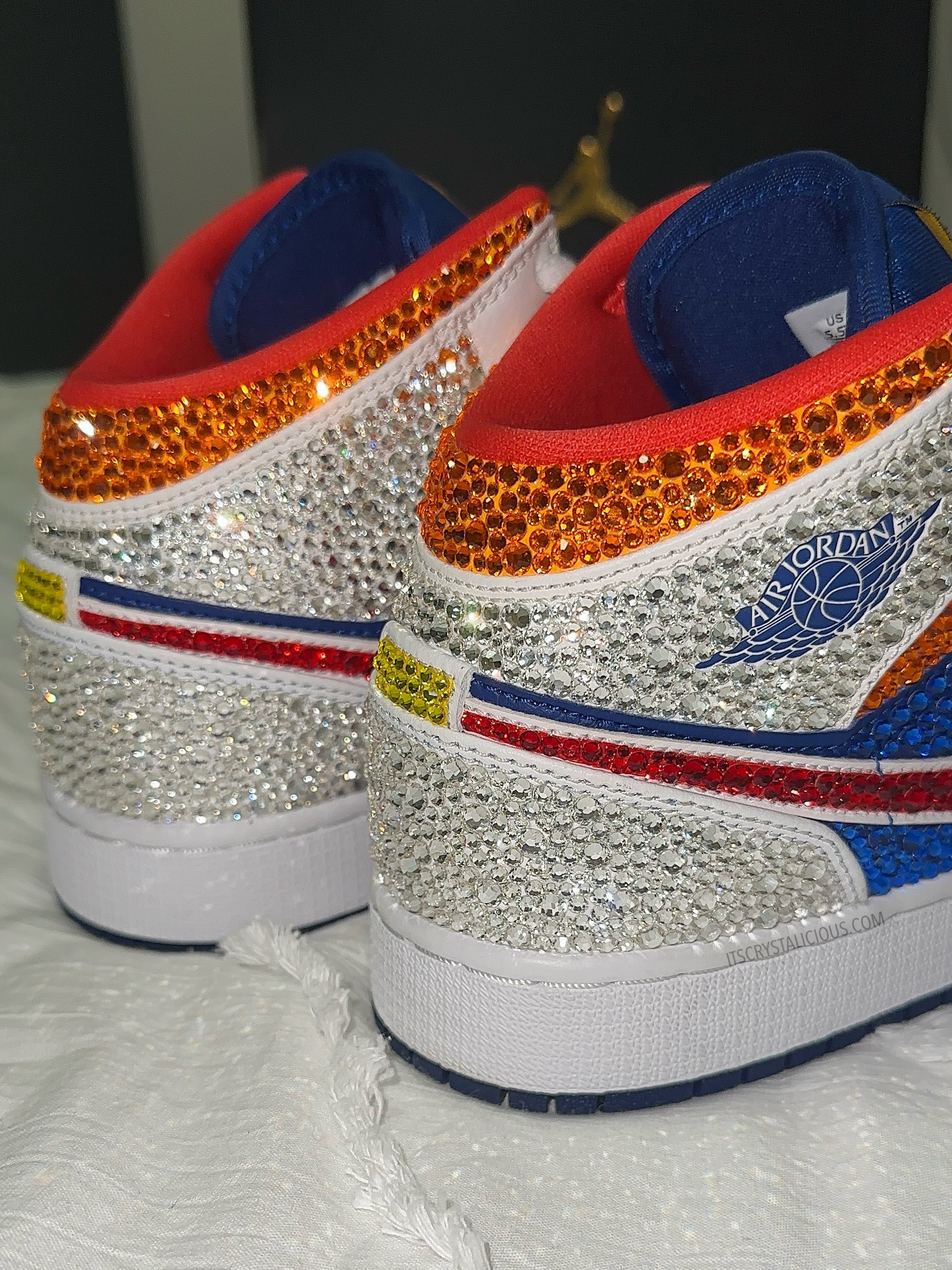 Pair of crystal embellished mid sneakers with blue, red, and white design on a textured white background