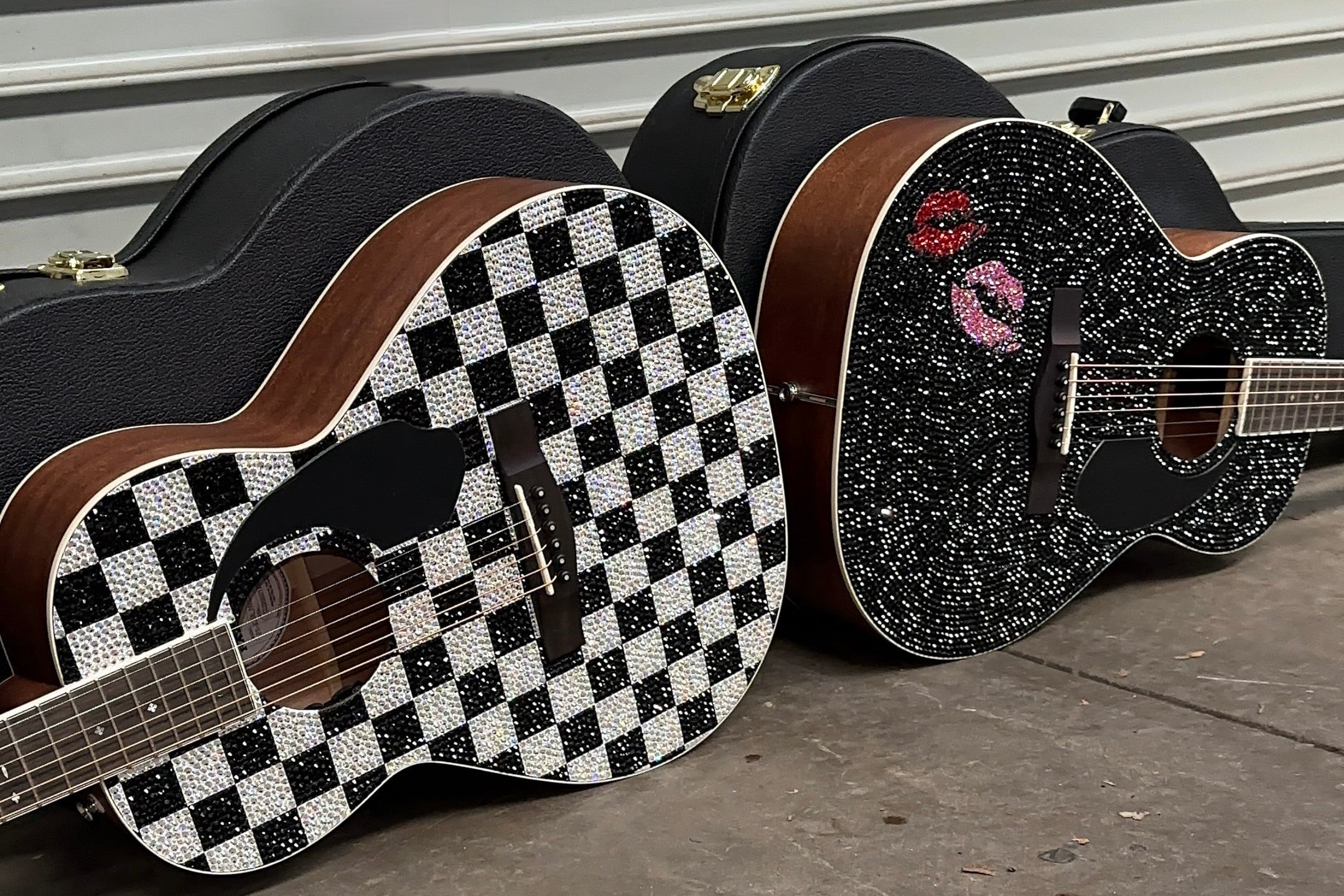 Two crystal guitars with unique finishes leaning against a corrugated metal wall.