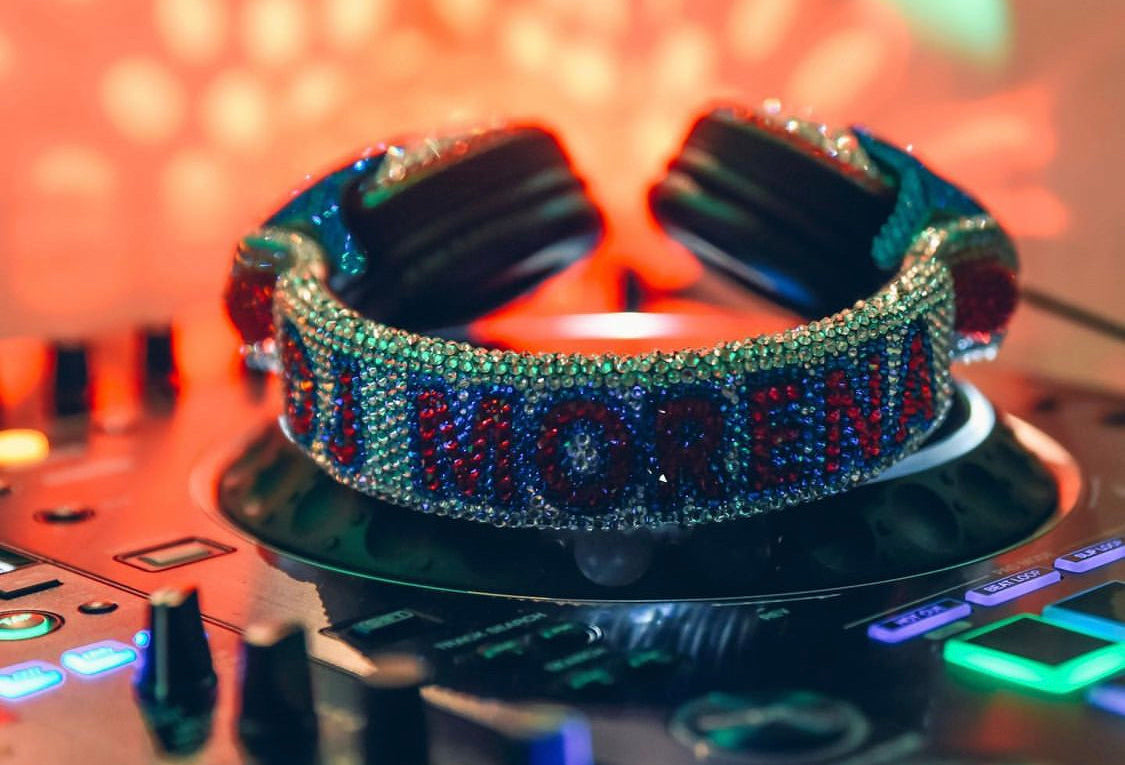 Decorative headband with 'MODENA' text on a DJ mixer with colorful lights
